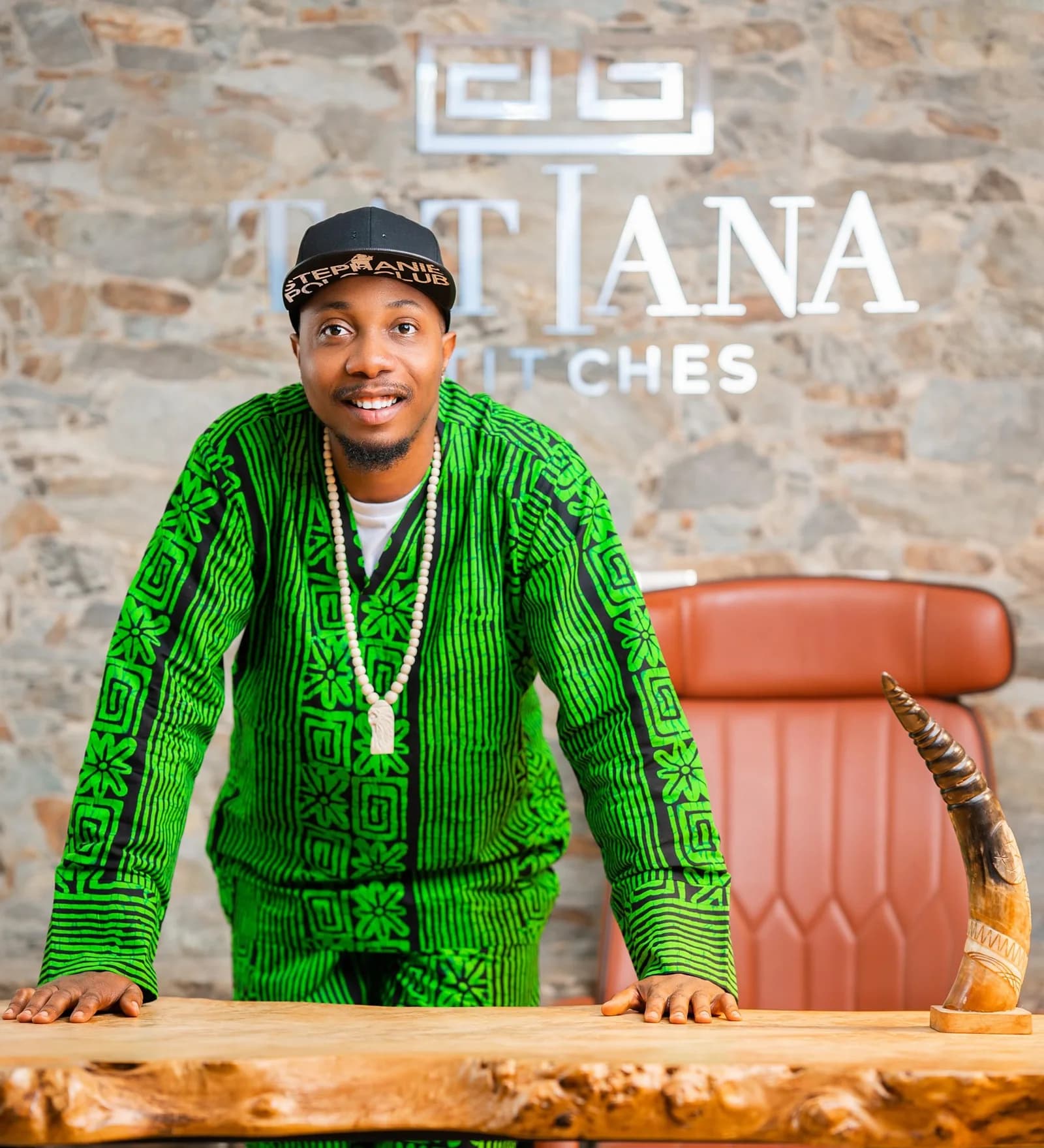 Chigbo Vitalis Agbo at his desk under the Tatiana Stitches sign